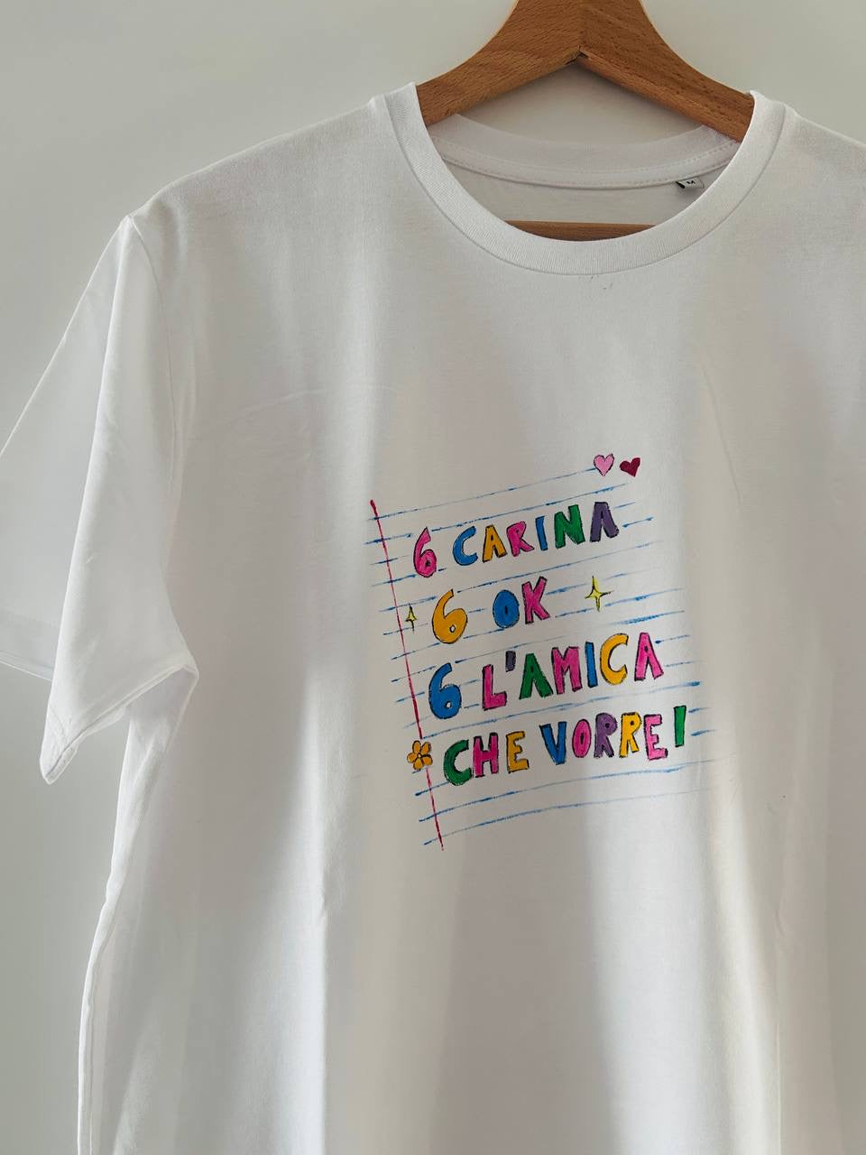 T-shirt 6 Carina 6 Ok dipinta a mano – vista frontale su gruccia outdoor